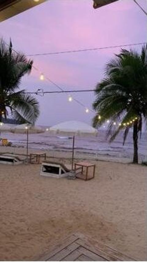 Atardecer rosado sobre la playa con luces colgantes