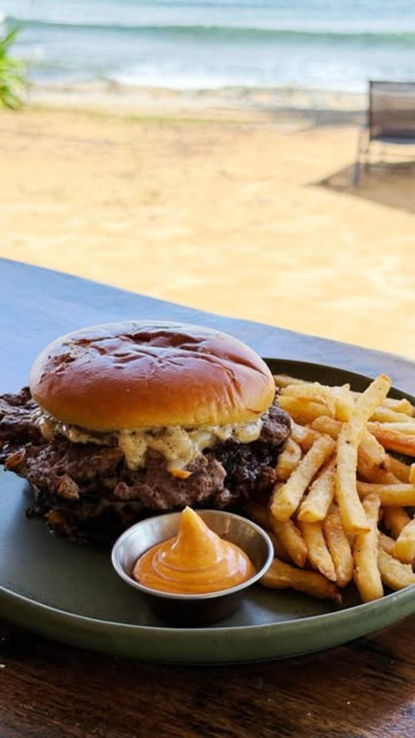 Hamburguesa con papas fritas sobre la mesa frente a la playa
